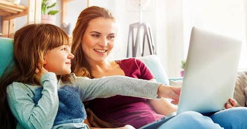 A Learning Coach using a laptop helps her elementary school student become more motivated to learn.